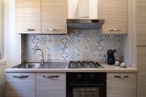 Une cuisine avec des meubles de rangement en bois, une cuisinière à gaz, un évier et un crédence décorée.