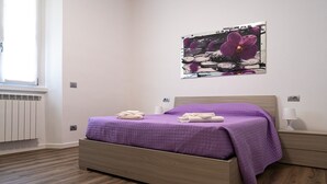 Une chambre à coucher avec un lit, un radiateur, une fenêtre et un tableau accroché au mur.