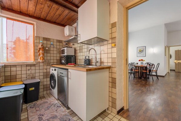 A compact kitchen with a washing machine, microwave, and sink.