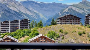 Une station de montagne comprenant plusieurs bâtiments en bois, dont une grande structure à plusieurs étages dotée de balcons et un plus petit bâtiment ressemblant à un chalet.