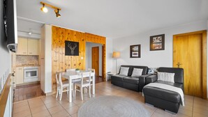 Un salon moderne comprenant un coin repas, des murs en bois, un canapé et un téléviseur.