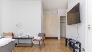 A modern bedroom with a bed, a desk, a chair, a TV, and a wardrobe.