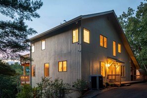 A modern two-story house with a wooden exterior, multiple windows, and a porch area.