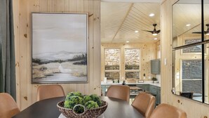 A dining area with a large painting, a wooden table, and chairs. - Views, Game Room, Pet-Friendly - Mountain Top Main House in Lovely Seven Devils (Seven Devils)