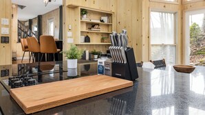 A modern kitchen with a central island, wooden shelves, and a dining area with chairs. - Views, Game Room, Pet-Friendly - Mountain Top Main House in Lovely Seven Devils (Seven Devils)