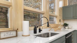 A kitchen with a stone wall, wooden cabinets, a marble countertop, and a sink with a modern faucet. - Views, Game Room, Pet-Friendly - Mountain Top Main House in Lovely Seven Devils (Seven Devils)