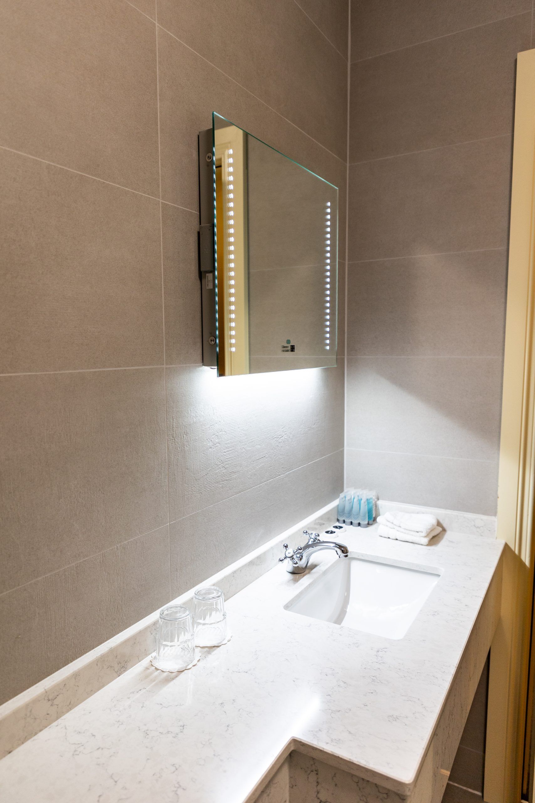 A modern bathroom with two sinks, a large mirror, and LED lights.