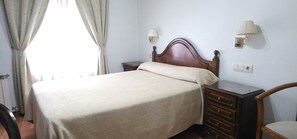 Une chambre à coucher comprenant un lit, des tables de chevet, une lampe, une chaise et une commode.