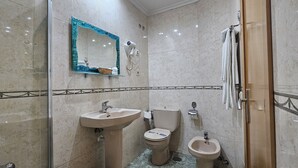 Une salle de bain équipée d’un lavabo, de toilettes, d’un bidet et d’un miroir avec un cadre décoratif.