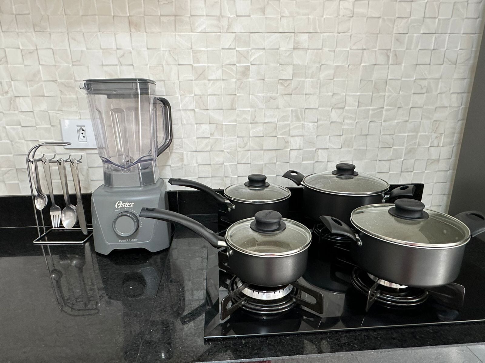 Una cocina con licuadora, ollas y estufa a gas.