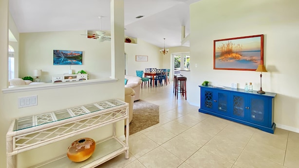 A spacious living area with a dining table and chairs, a blue cabinet, and a glass shelf with decorative items. - Sunset Pines, Sleeps 6, heated pool, 2 Dog ok (Rotonda West)