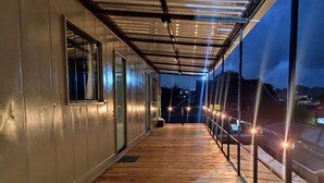 A covered outdoor area with a wooden deck, metal railings, and string lights. -  Residencial Taulois Canela Centro (Canela)