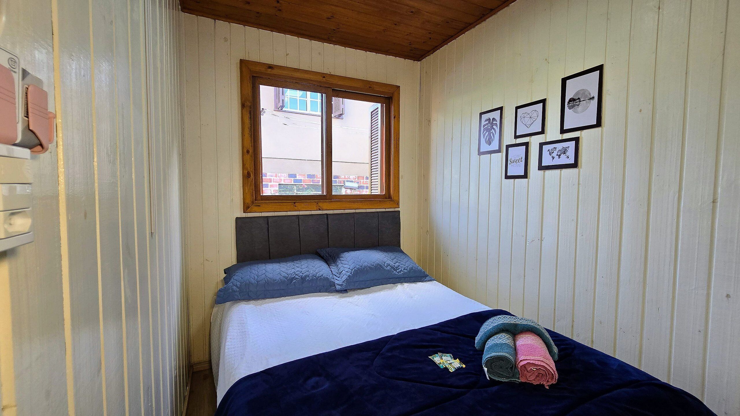 Un dormitorio con cama, ventana y cuadros en la pared.