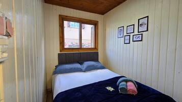 Un dormitorio con cama, ventana y cuadros en la pared.