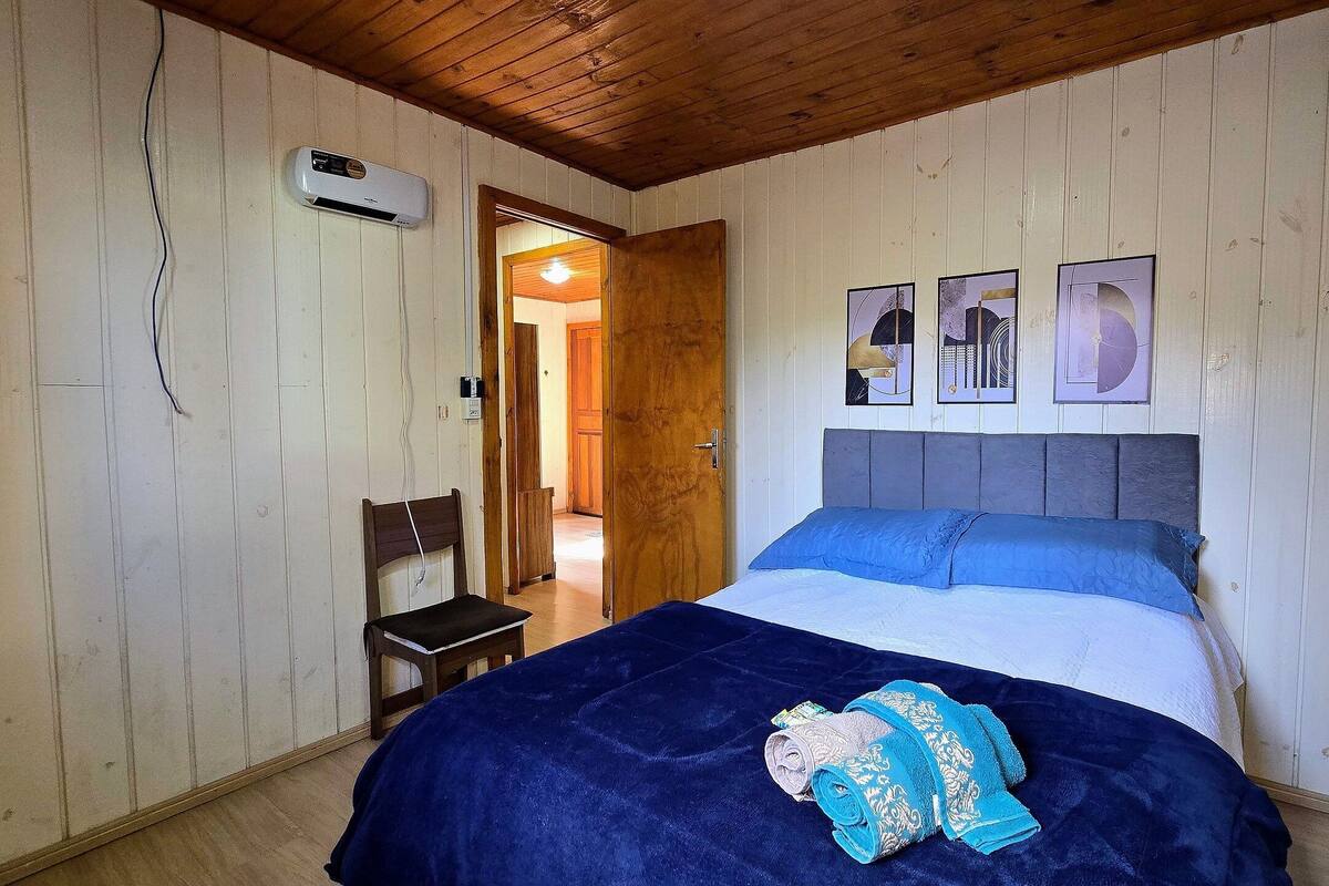 Un dormitorio con cama, una silla, una puerta y una obra de arte en la pared.