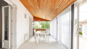 A modern kitchen with white cabinets, a wooden ceiling, and a large window.