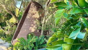 A wicker chair in a garden with lush greenery and trees. - GuestHost - Charming Pool Villa Porto Rotondo (Porto Rotondo)