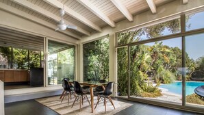 A spacious room with a dining table, chairs, and a view of a swimming pool. - GuestHost - Charming Pool Villa Porto Rotondo (Porto Rotondo)