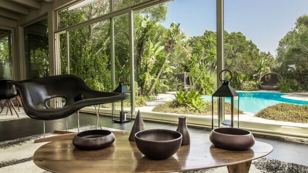 A modern interior with a large window overlooking a pool and lush greenery. - GuestHost - Charming Pool Villa Porto Rotondo (Porto Rotondo)