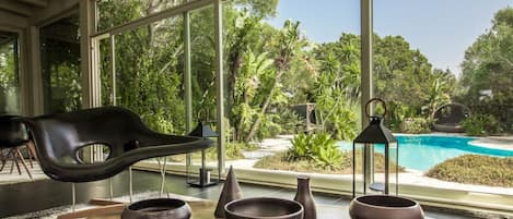 A modern interior with a large window overlooking a pool and lush greenery.