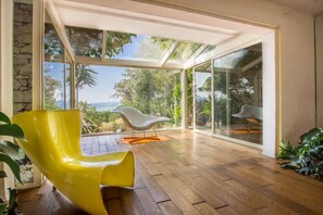 A modern interior with a wooden floor, a yellow chair, and a view through large glass doors.