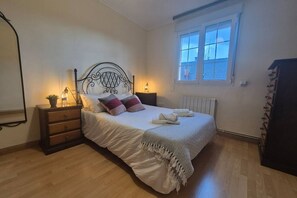 A bedroom with a bed, bedside tables, a window, and a radiator.