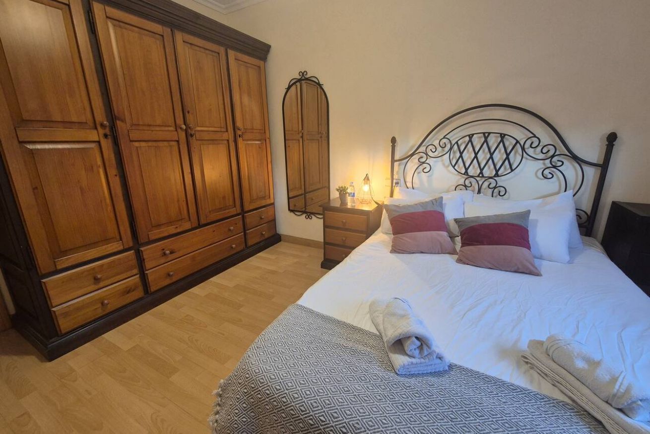 Une chambre à coucher avec un lit, une armoire en bois et un miroir.
