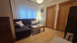 Uma sala de estar mobiliada com sofá, mesa de centro, luminária e uma porta.
