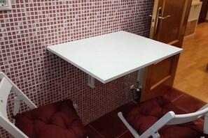 A white shelf unit against a tiled wall, a cushioned bench, and a wooden door.