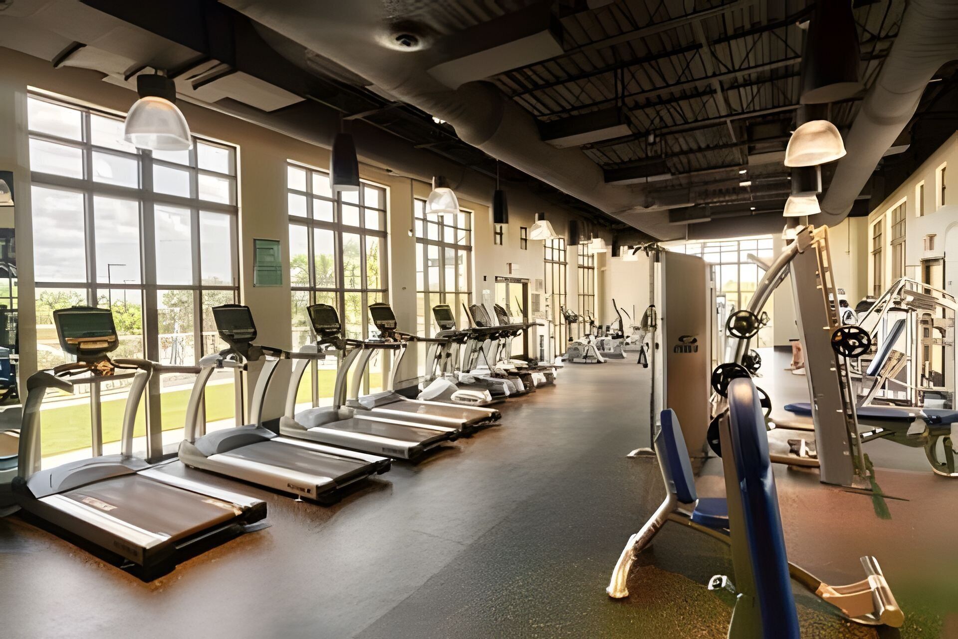 Ein Fitnessstudio mit Laufbändern, Crosstrainern und Gewichten.