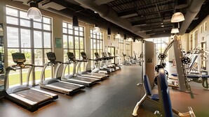 Une salle de sport équipée de tapis de course, de vélos elliptiques et de matériel de musculation.