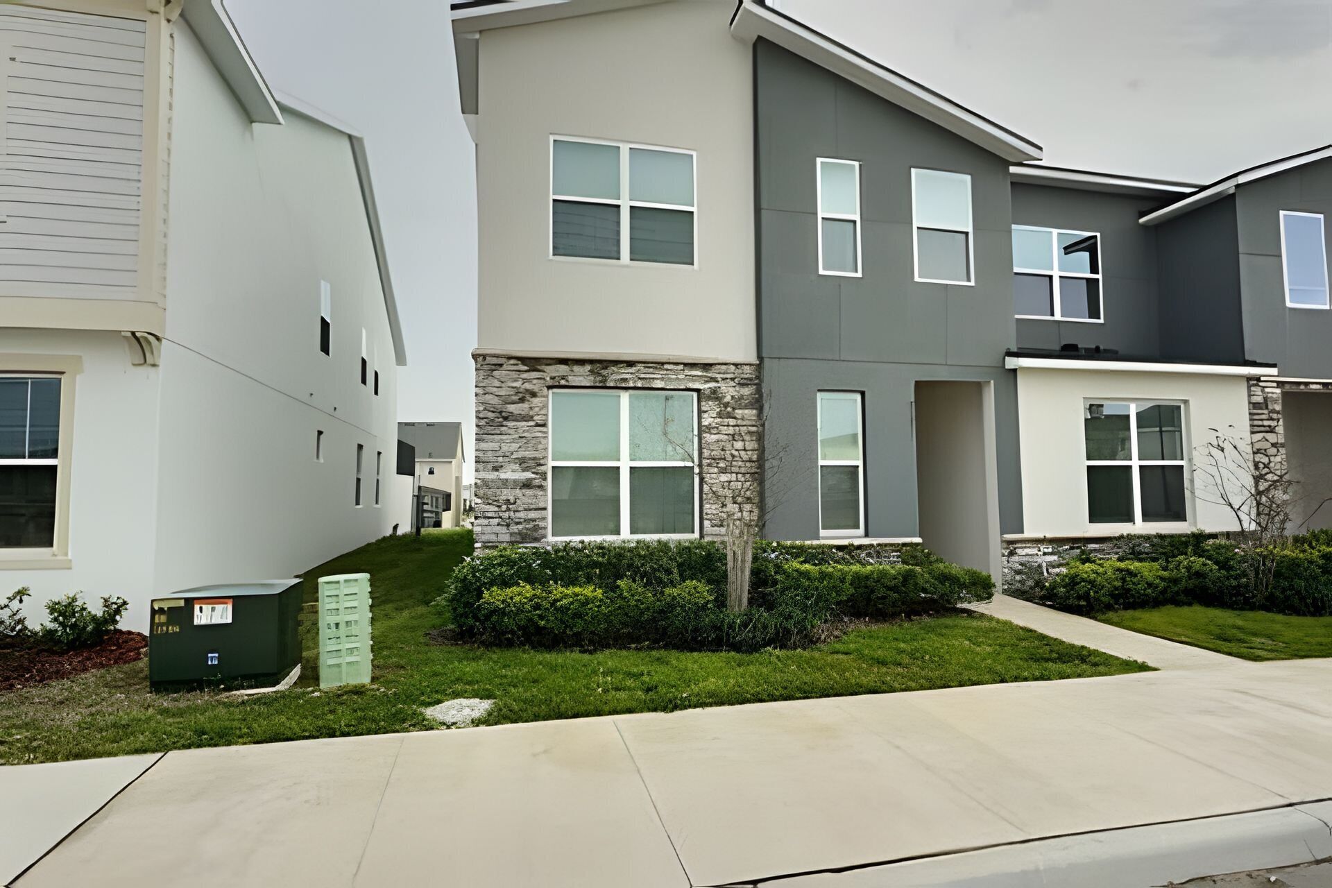 A row of modern townhouses with stone accents, large windows, and a well-maintained lawn.