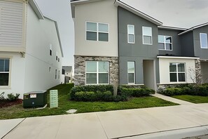A row of modern townhouses with stone accents, large windows, and a well-maintained lawn. - Modern 6BR Villa Heated Pool Solara Resort (Kissimmee)
