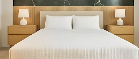 Un letto rifatto con lenzuola bianche, due comodini con lampade e una parete di grandi dimensioni con effetto marmo sopra il letto.