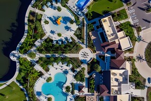 An aerial view of a resort with a central pool, multiple buildings, and surrounding greenery. - Modern 6BR Villa Heated Pool Solara Resort (Kissimmee)