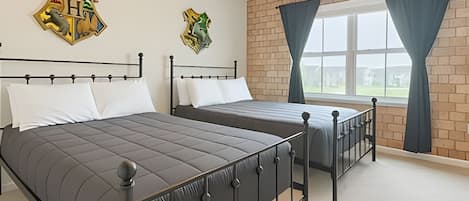 A bedroom with two beds, a brick wall, and a window with curtains.