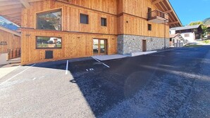 Un bâtiment moderne en bois, doté de grandes fenêtres et d’une base en pierre, situé dans un parking.