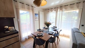 Une cuisine moderne avec une table à manger pour quatre personnes, un canapé et une grande fenêtre avec des rideaux.