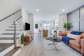 Una sala de estar moderna con escalera, cocina y comedor.