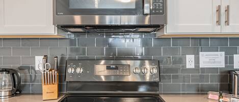Una cocina con microondas, horno y estufa de acero inoxidable.