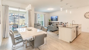 A modern apartment with a dining area, kitchen, and living space. - Luxury 4bd/3ba Home Storey Lake (Kissimmee)