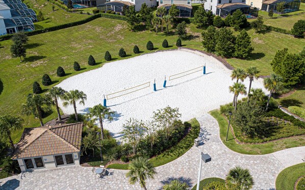 An aerial view of a landscaped area with a tennis court, palm trees, and a building with a tiled roof. - 396 - 4bd/3ba Luxurious Homechampions Gate Resort (Kissimmee)