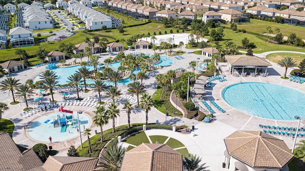 Un resort con varias piscinas, palmeras y áreas de descanso.