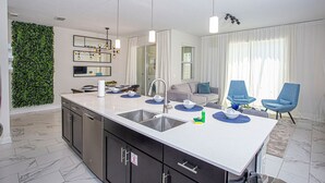 Una cocina moderna con una isla central, electrodomésticos de acero inoxidable y un jardín vertical verde.