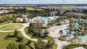 Un resort con piscina central, varias zonas de descanso y un campo de golf al fondo.