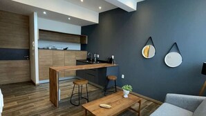 Un espace de vie moderne comprenant une cuisine, un canapé gris, un plancher en bois et une table basse.