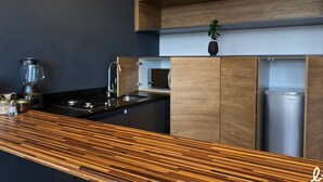 Une cuisine moderne dotée d’un plan de travail en bois, d’un évier encastré, d’un mixeur et d’un réfrigérateur en acier inoxydable.