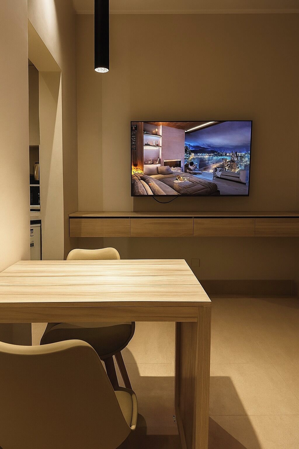 Una sala de estar moderna con un televisor de pantalla plana montado en la pared, una mesa de comedor de madera y un área de estar acogedora.