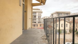 A balcony with a concrete floor, metal railing, and a view of neighboring buildings. - Charming with balcony in the heart of the 7th (Lyon)