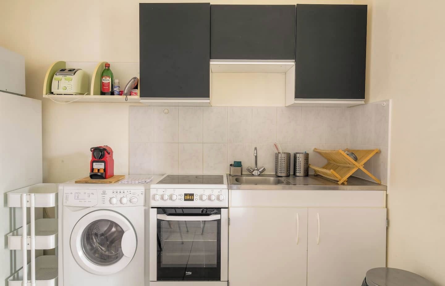 A compact kitchen with a washing machine, a stove, and a sink.